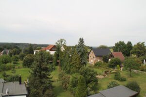 Blick auf eine grüne Wohngegend mit Häusern, Gärten und vielen Bäumen unter einem leicht bewölktem Himmel.